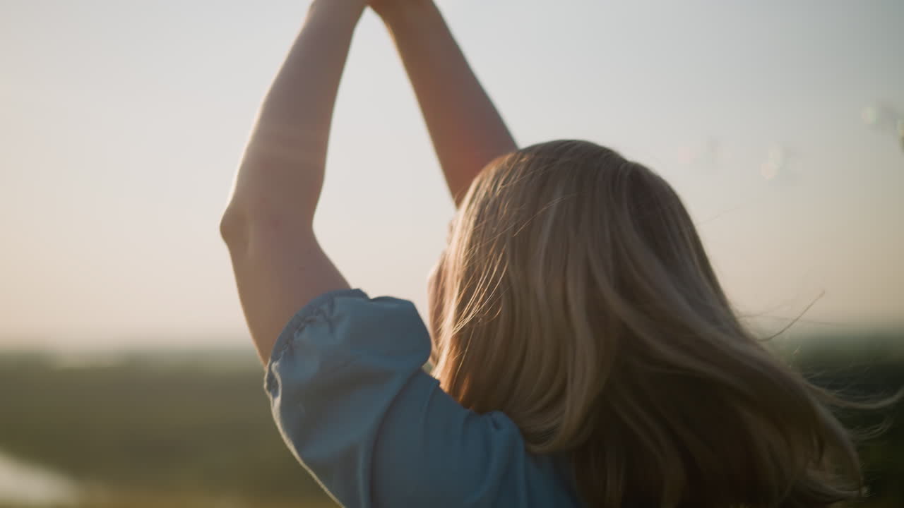 파란 드레스를 입은 여성의 클로즈업, 그녀의 손은 기게 올려, 그녀의 얼굴에 미소와 함께 회전, 거품이 배경에 떠, 순수한 행복과 무모한 기의 순간을 포착.