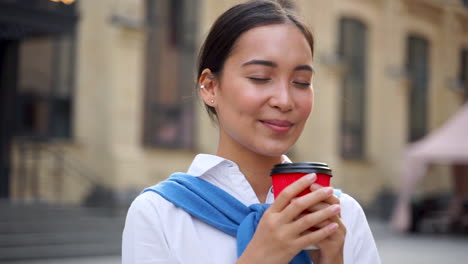 porträt einer frau, die draußen einen kaffee trinkt