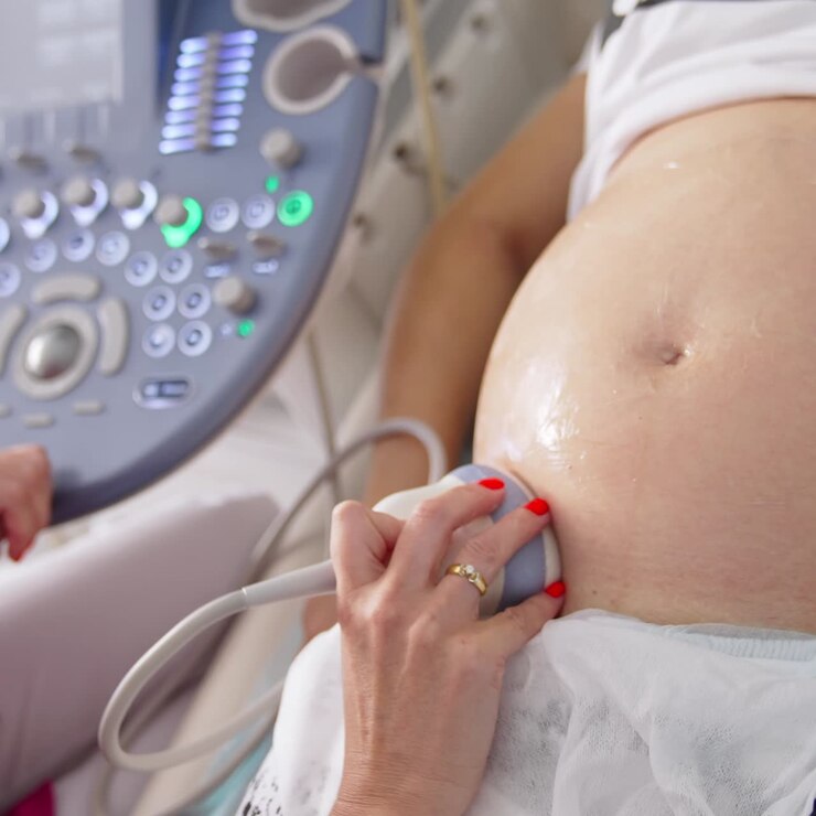 Medico che esegue un'ecografia a una donna incinta. Ostetrico che muove la sonda sulla pancia della futura mamma. Moderne apparecchiature mediche per ecografia. Primo piano.
