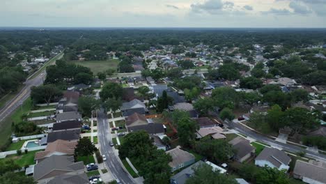 main intersection road in small suburb neighborhood of florida at cloudy day. luxury houses and villas in rich district. aerial flyover wide shot. dusk scene