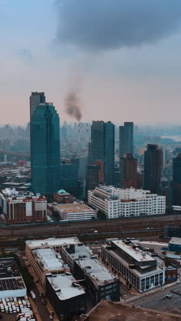 black smoke rising over the skyline of new york. city panorama at sunset from aerial perspective. vertical video