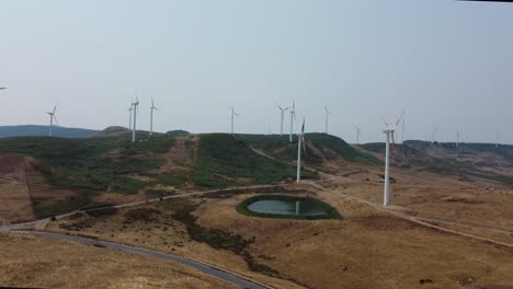 drone filming wind turbines above the hills