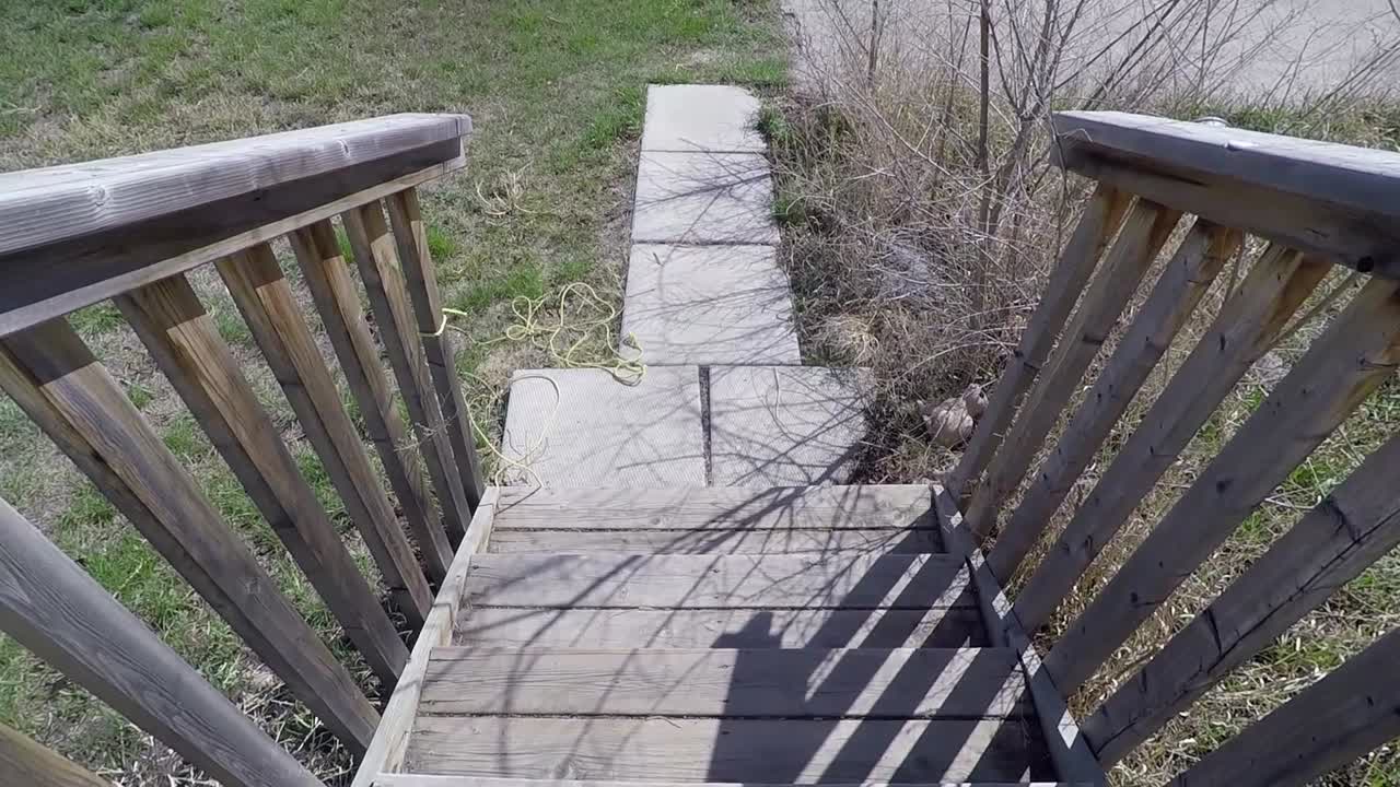 여름에 길 건너편의 과 버려진 건물을 바라보는 집 앞 문의 나무 계단에 서 있습니다.