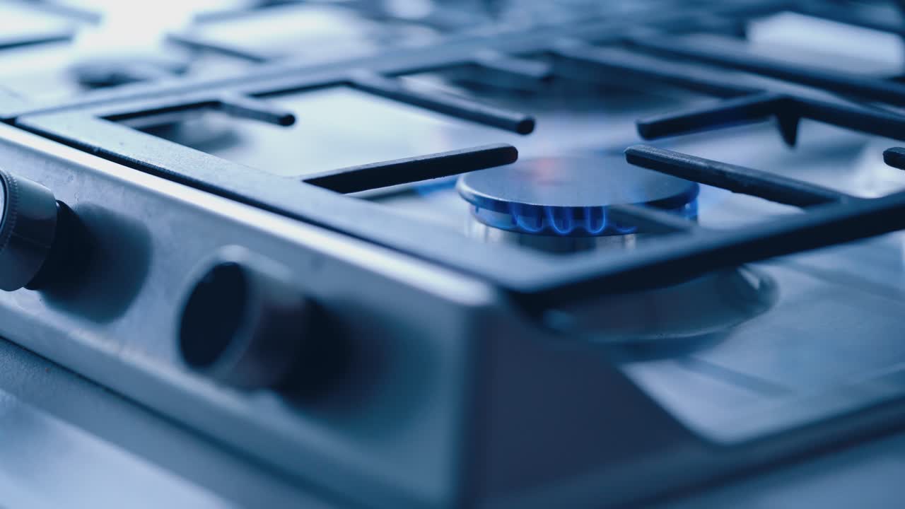 Switching on the gas cooker. Female's hand turning on the gas on a stove. Fire lights up on the electric cooker. Close-up.
