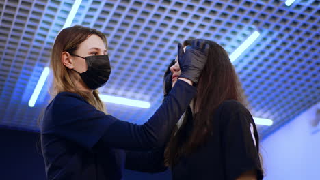adult brunette lady is prepared for eyebrow make up in salon. cosmetologist sticks the ruler to the client's forehead. low angle view.