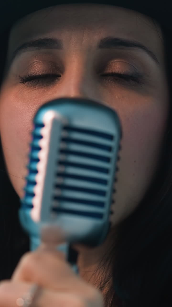 얼굴 없는 가수가 가죽 재을 입고, 반지 장식 손으로 빈티지 마이크를 들고 있는 클로즈업.