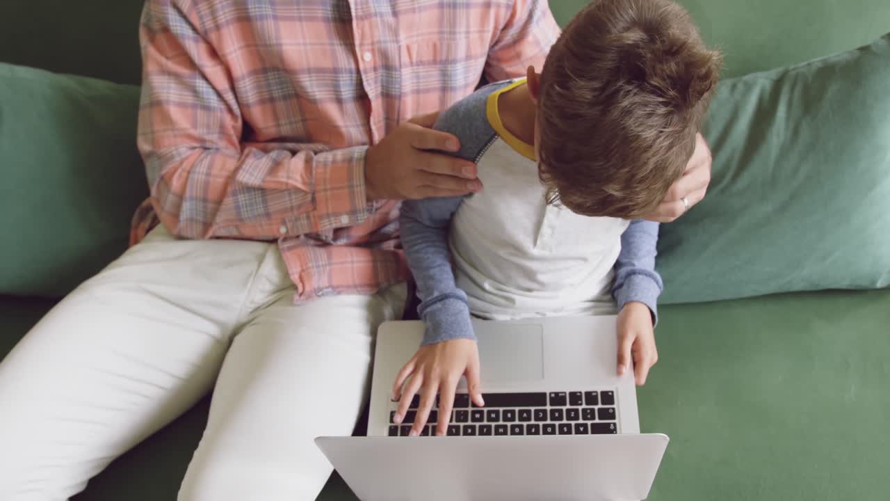 padre e hijo usando computadora portátil en el sofá en casa 4k