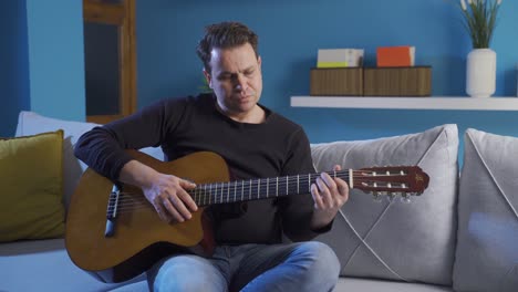 Emotional-and-sad,-graceful-and-calm-man-living-in-his-grief-and-distress,-strumming-his-guitar.