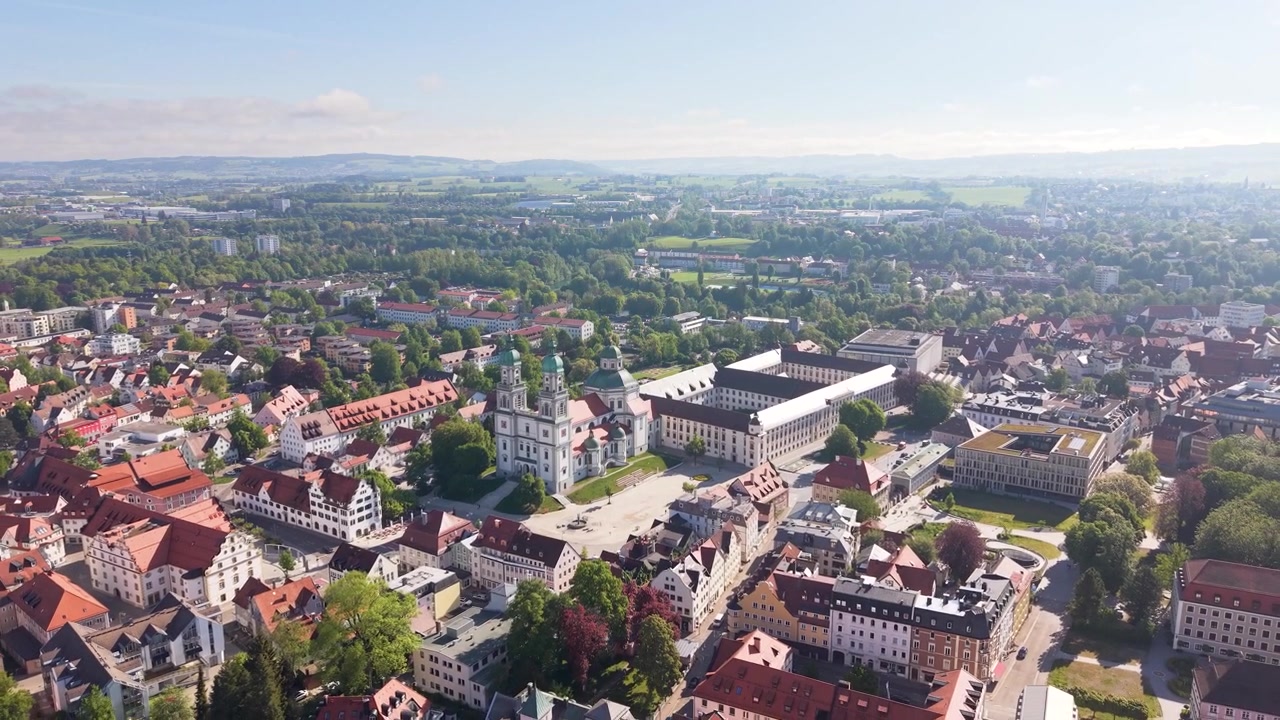 Ripresa con drone in allontanamento del centro di Kempten Allgäu in Germania, che mostra architettura storica, torri di chiese, quartieri residenziali e un vasto skyline bavarese durante una giornata di sole in UHD