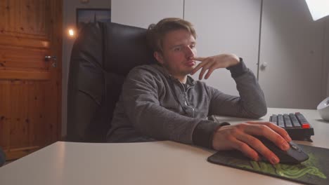 a young man is using his fingers to flip his lips as he sits in front of his home computer