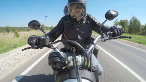 couple bikers in a leather jacket riding a motorcycle on the road