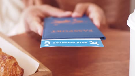person holding passport and boarding pass in a cafe