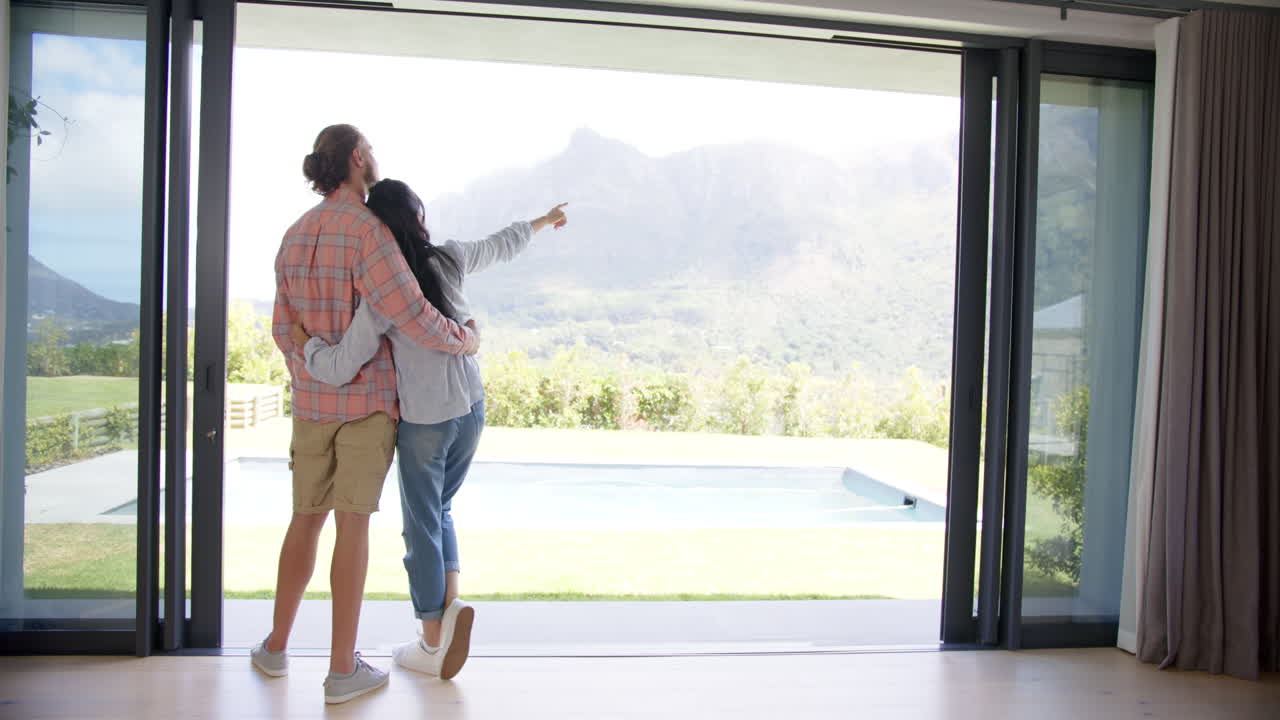 A diverse couple is admiring the view from their home, copy space