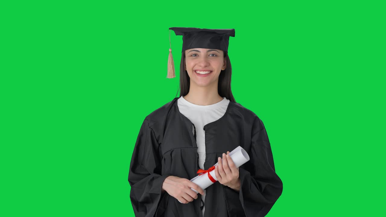 Ragazza indiana laureata felice che tiene in mano la laurea. Schermo verde.