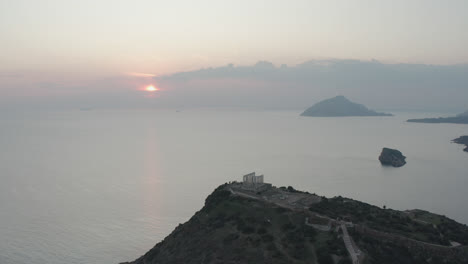 drone shot of ancient ruins in greece with sun setting in background