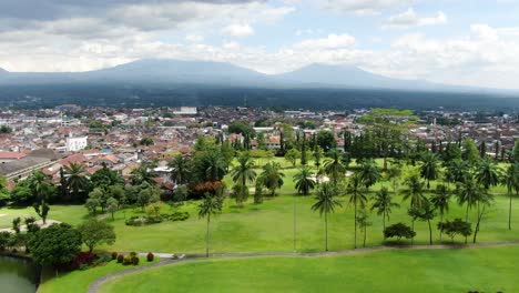 Palmen,-Indonesische-Stadt-Und-Bergkette-Im-Horizont,-Luftbild