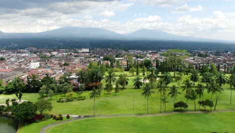 palmeras, ciudad indonesia y cordillera en el horizonte, vista aérea