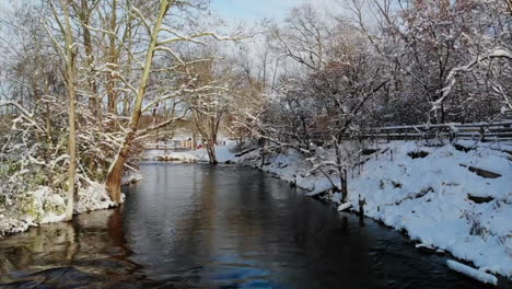 Aerial-sunrise-view-of-rushing-creek-in-winter-forest-in-Michigan