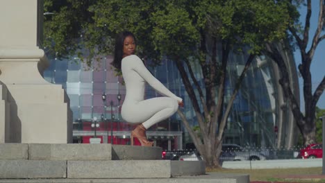 With-glass-buildings-in-the-background,-a-young-girl-in-a-white-bodysuit-enjoys-the-city