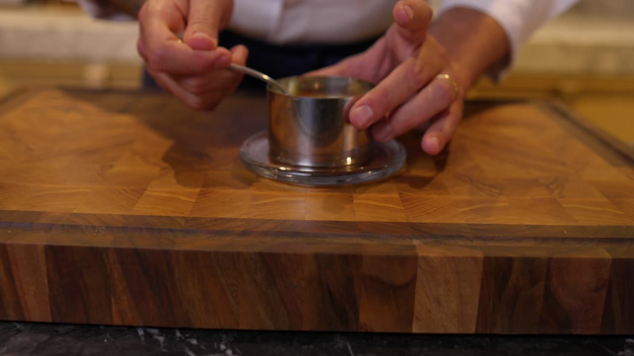 chef levantando la prensa de plata redonda para revelar el tártaro de la carne