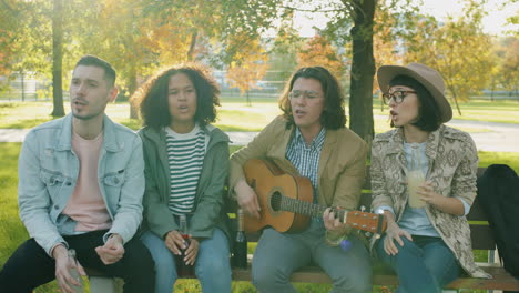 friends singing and playing guitar in a park