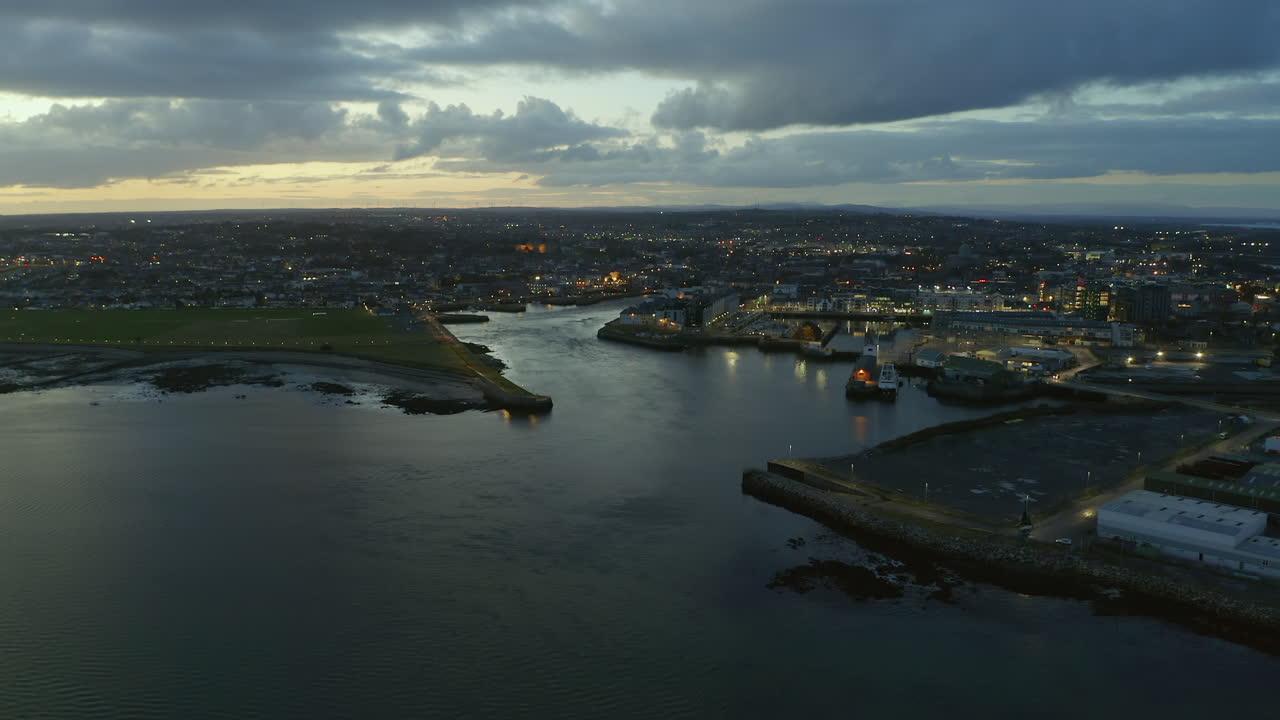 Aerial view of Galway city at twilight, showcasing coastal city lights from the sea