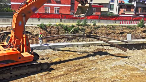 la excavadora en el sitio de construcción mueve barras de acero