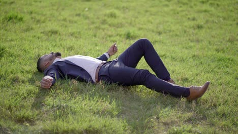 man in suit lying on green lawn