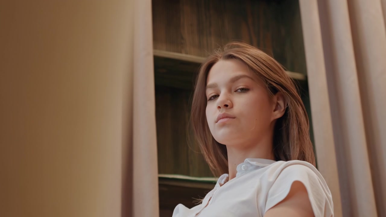 Giovane donna che si acconcia i capelli allo specchio, sessione di cura personale composta con illuminazione soffusa, movimento espressivo ed estetica moderna, preparazione per la giornata con un'atmosfera editoriale e una sicurezza senza sforzo.