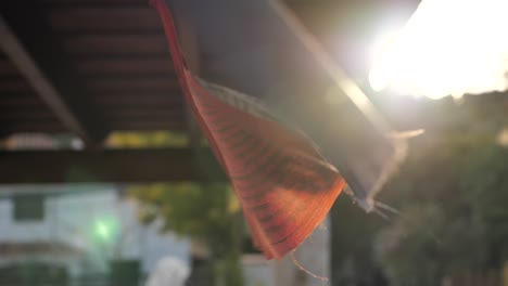 Buddhist-nepali-flags-waving-with-soft-wind-in-a-terrace-at-sunset,-slow-motion