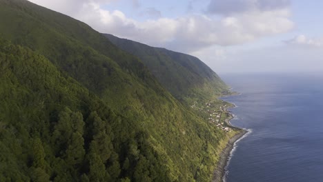 Acantilados-Verdes-Exuberantes-Sobre-El-Océano-Atlántico-Con-Un-Pueblo-Rural,-Isla-De-São-Jorge,-Azores,-Portugal