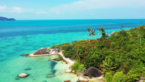 Pequeña-Isla-Tropical-Con-Palmeras,-Playas-Aisladas-De-Arena-Blanca-Y-Rocas-De-Granito-En-La-Orilla-Bañadas-Por-Olas-De-Océano-Turquesa-Y-Cristalino