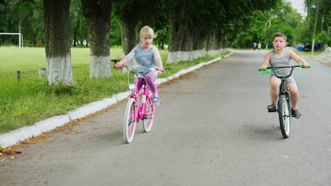 Zwei-Unbeschwerte-Kinder---Ein-Mädchen-Und-Ein-Junge-Fahren-Mit-Dem-Fahrrad-Auf-Der-Straße