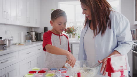 Glücklicher-Hispanischer-Junge-Im-Teenageralter-Und-Seine-Großmutter-Backen-In-Der-Küche-Kuchen,-High-Five-Und-Umarmen-Sich,-Aus-Nächster-Nähe