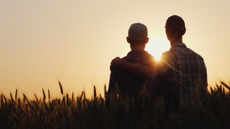 two young men hugging against the backdrop of the sunset looking forward to the horizon