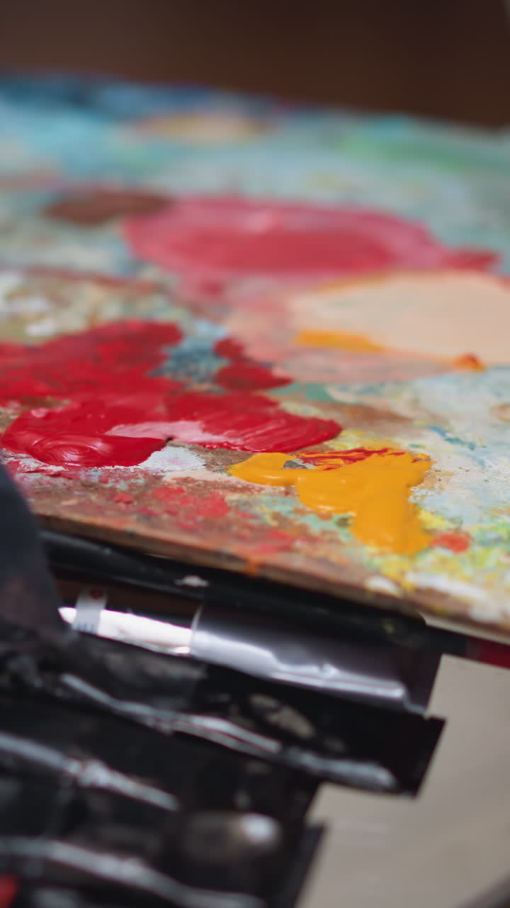 mesa con paleta de colores y pinceles. artista enjuaga pincel en vidrio lleno de agua quitando pintura. herramientas esenciales para la fabricación de arte