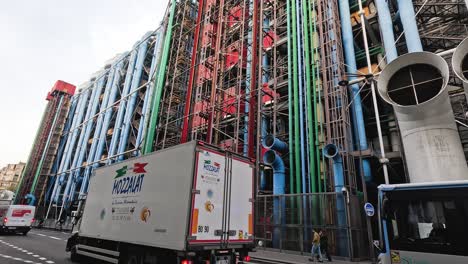 vehicles pass by a vibrantly colored building facade.