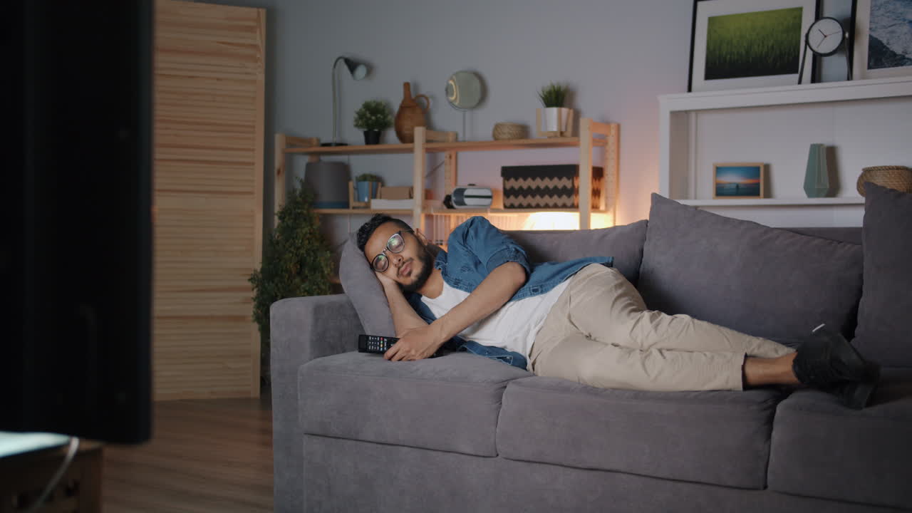 Man sleeping on couch while watching TV