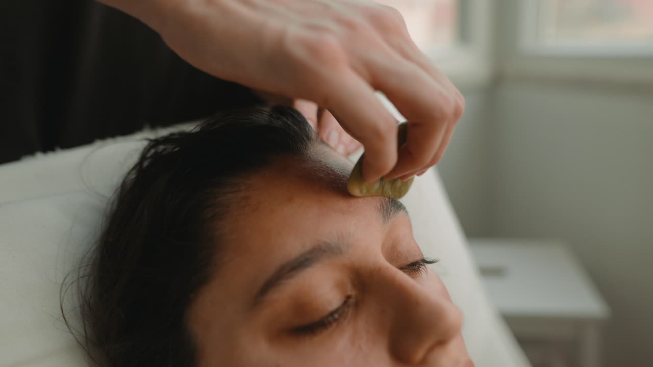 Nærbillede af kvinde, der får Gua Sha ansigtsmassage