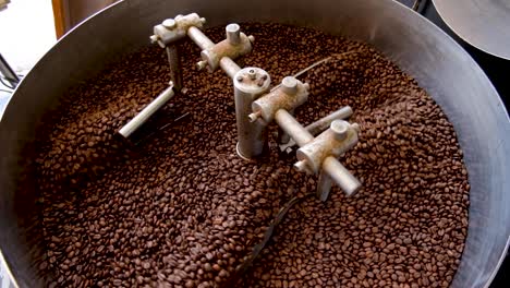 top down view of freshly roasted golden brown arabica coffee beans cooling down during roasting process in industrial coffee roasting machine