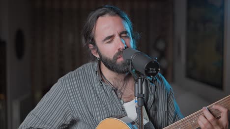 man singing and playing acoustic guitar at home