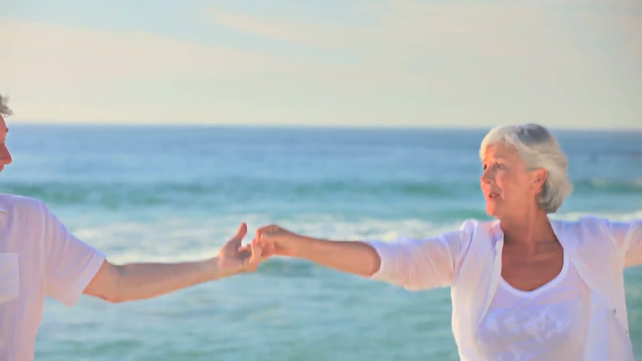 Coppia matura che balla e ride su una spiaggia