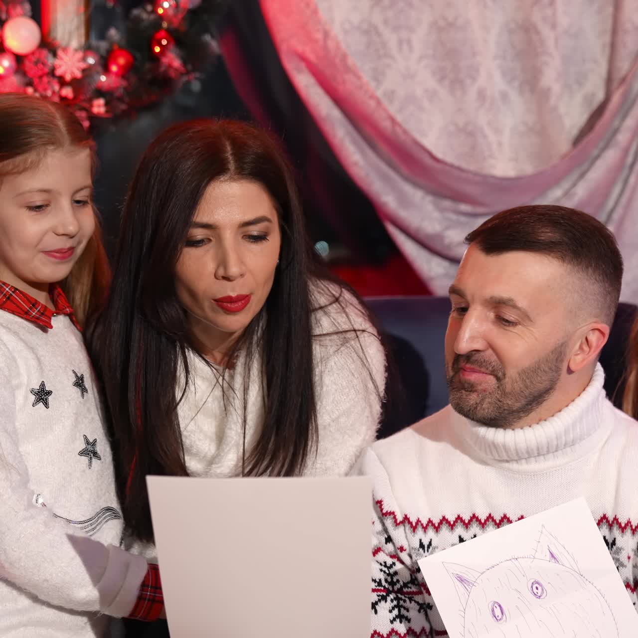 Little sisters looking at their handmade pictures while spending time at home with their parents. Children waiting for the New Year