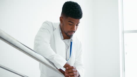 Stressed-Male-Doctor-Wearing-White-Coat-Standing-On-Stairs-In-Hospital-Suffering-With-Burnout