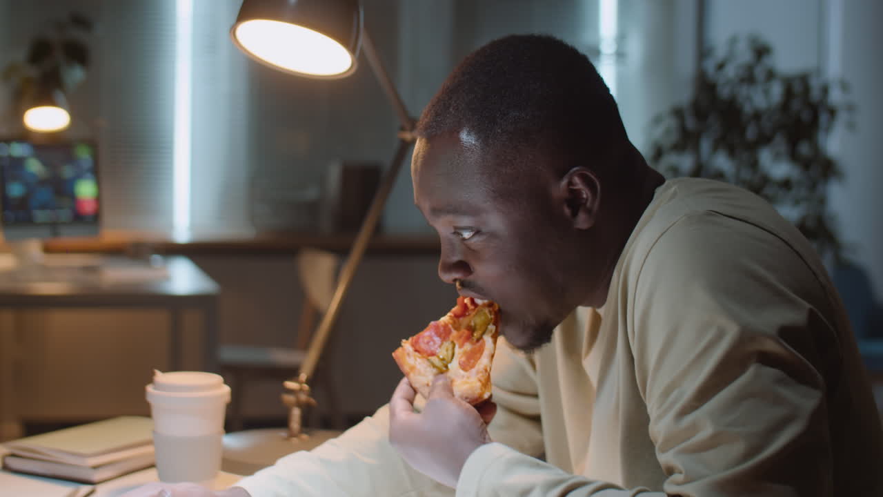 Man Eating Pizza while Working in Office during Night