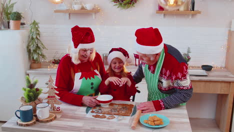 funny senior grandparents and granddaughter playing with flour smearing on face at christmas kitchen