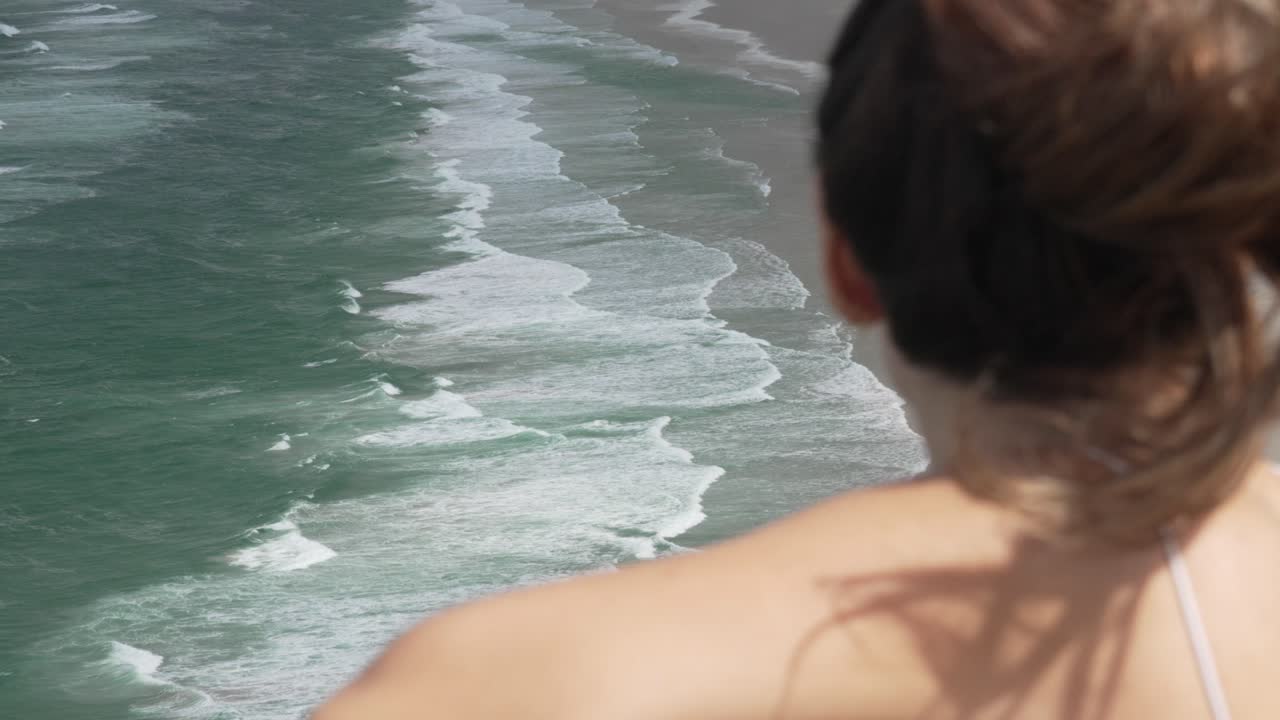 Woman admiring the beautiful ocean waves from a cliff
