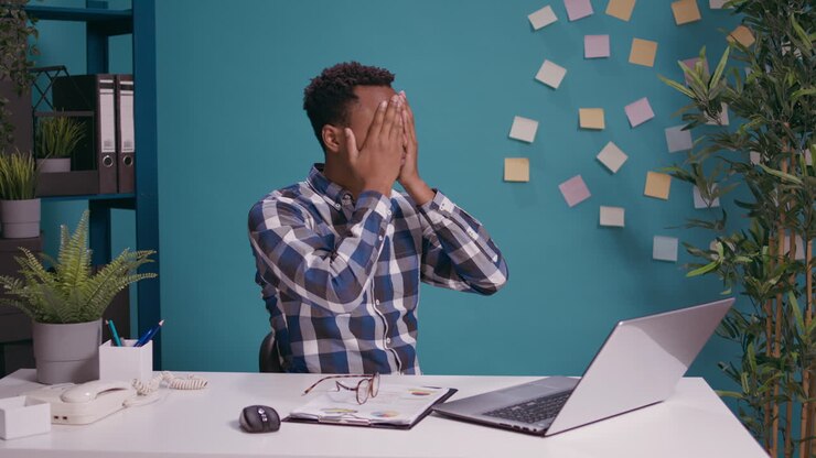Impiegato stupito che fa il simbolo delle tre scimmie sagge alla scrivania
