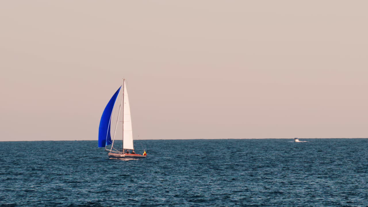 Small ship with a blue sails moving on the sea in Golfe-Juan, France