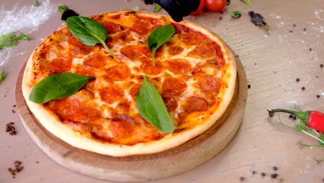 cook puts spinach leaves on pizza salami hands in rubber gloves.